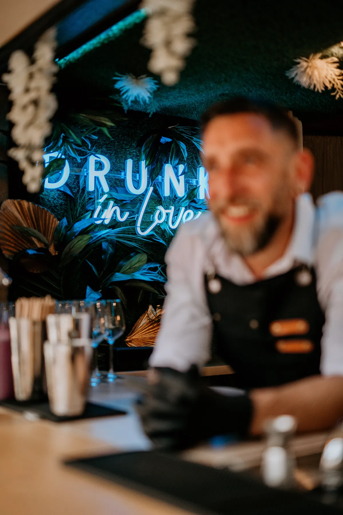 Barman souriant derrière le comptoir devant le néon Drunk in Love
