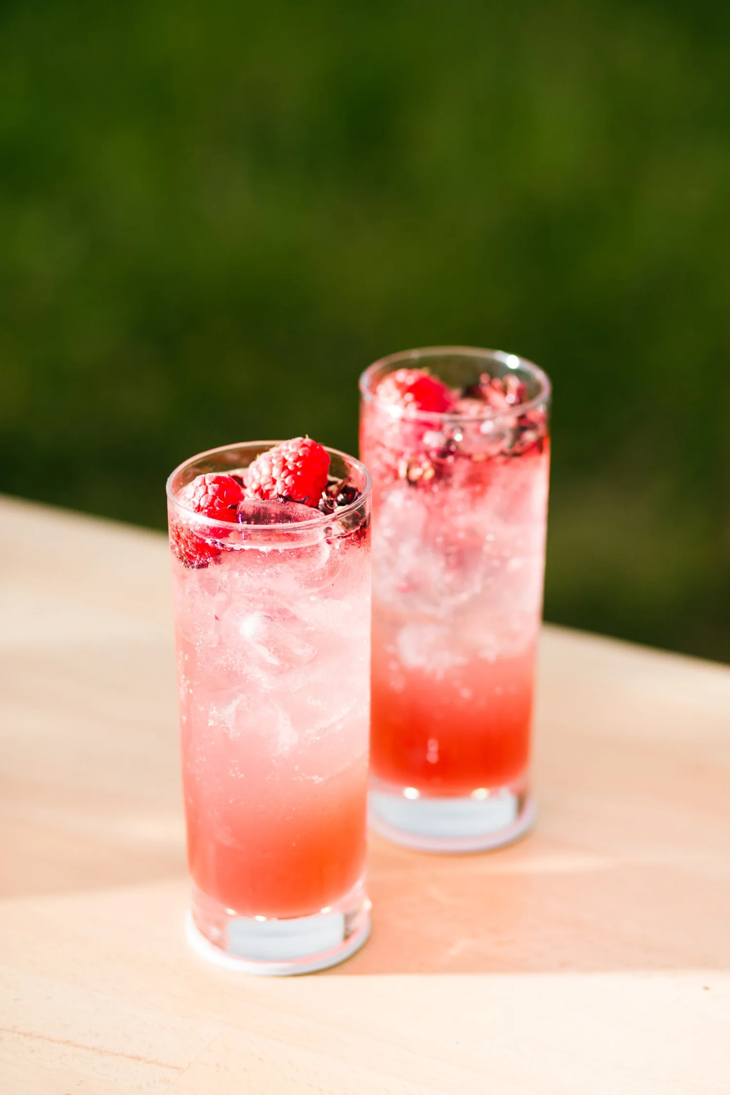Deux cocktails longs aux framboises et fleurs d'hibiscus, dégradé rose et rouge