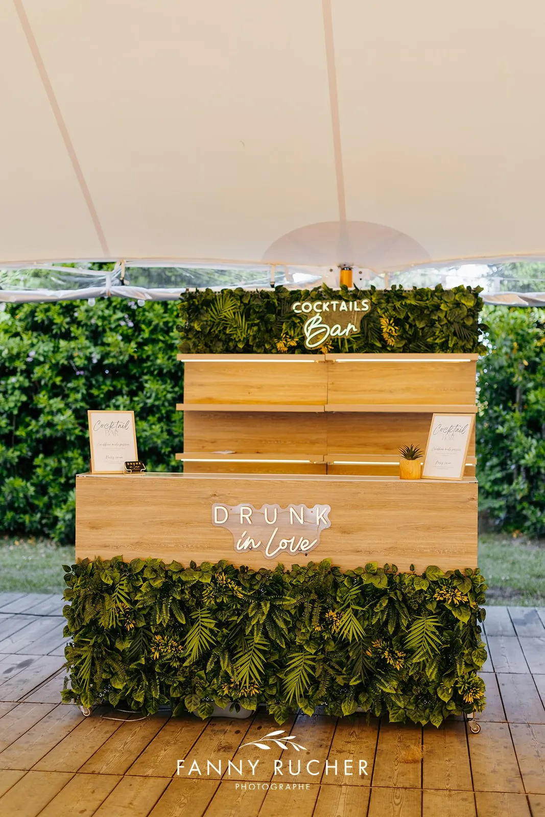 Bar à cocktails en bois et mur végétal sous un chapiteau