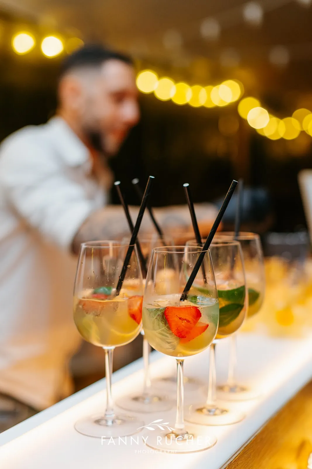 Spritz alignés sur un bar lumineux, pailles et fruits frais